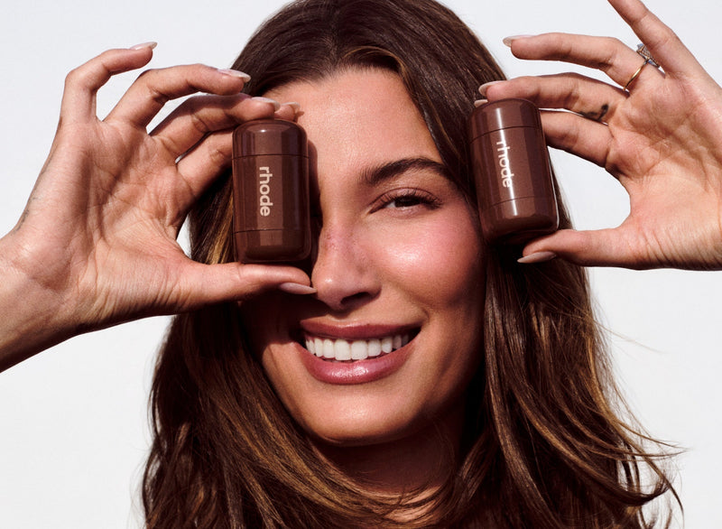 Woman smiling, holding two isoua bottles up to her face